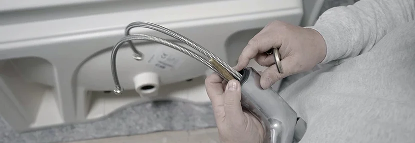 Person befestigt Schläuche an Wasserhahn